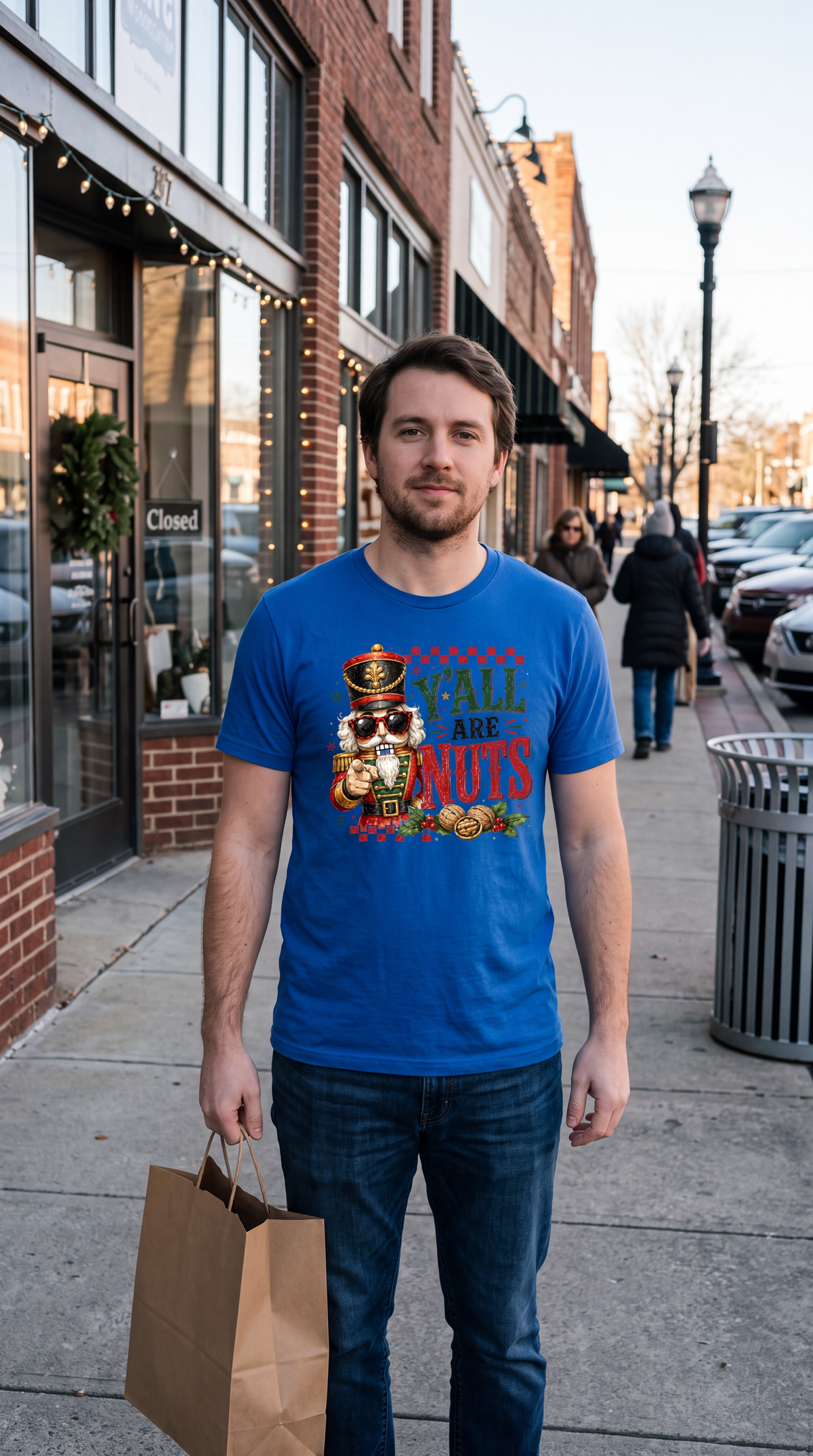 Man wearing blue Y’all Are Nuts nutcracker Christmas shirt outdoors in a casual holiday outfit
