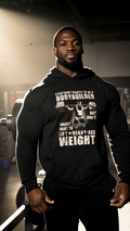Man wearing black gym hoodie with bodybuilding quote graphic lifting weights in gym