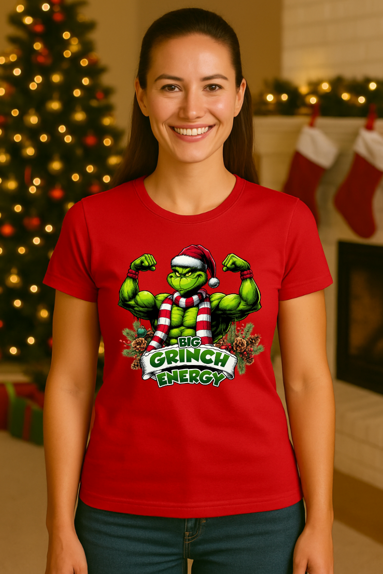 Woman wearing a red holiday muscle-energy graphic t-shirt, smiling in front of a decorated Christmas tree and festive fireplace setting.
