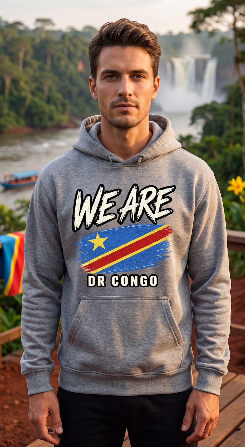 A man wearing a heather gray hoodie with a graphic print of the Democratic Republic of Congo flag and the text 'WE ARE DR CONGO' stands outdoors in front of a waterfall and lush green landscape.