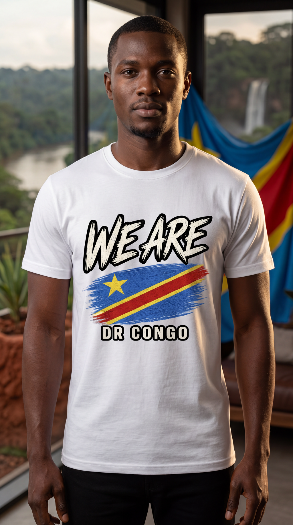 A man wearing a white graphic t-shirt with 'WE ARE DR CONGO' and a stylized flag design, standing in front of a window with a scenic view.