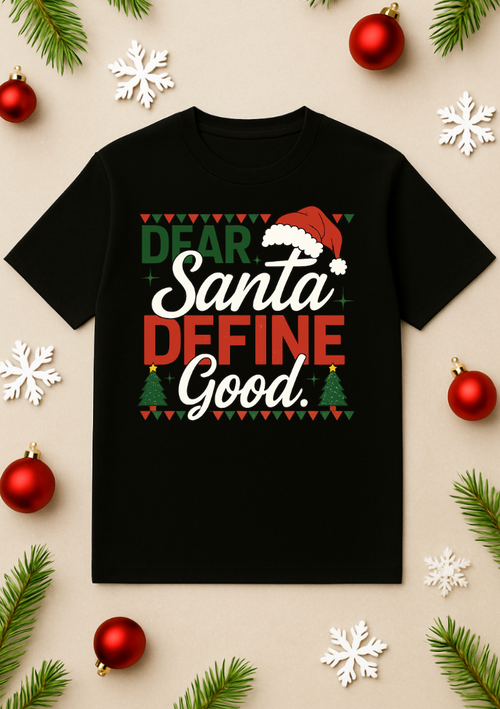 Black Christmas T-shirt with “Dear Santa Define Good” graphic, Santa hat design, and holiday colors displayed on a beige background with ornaments, snowflakes, and pine branches.