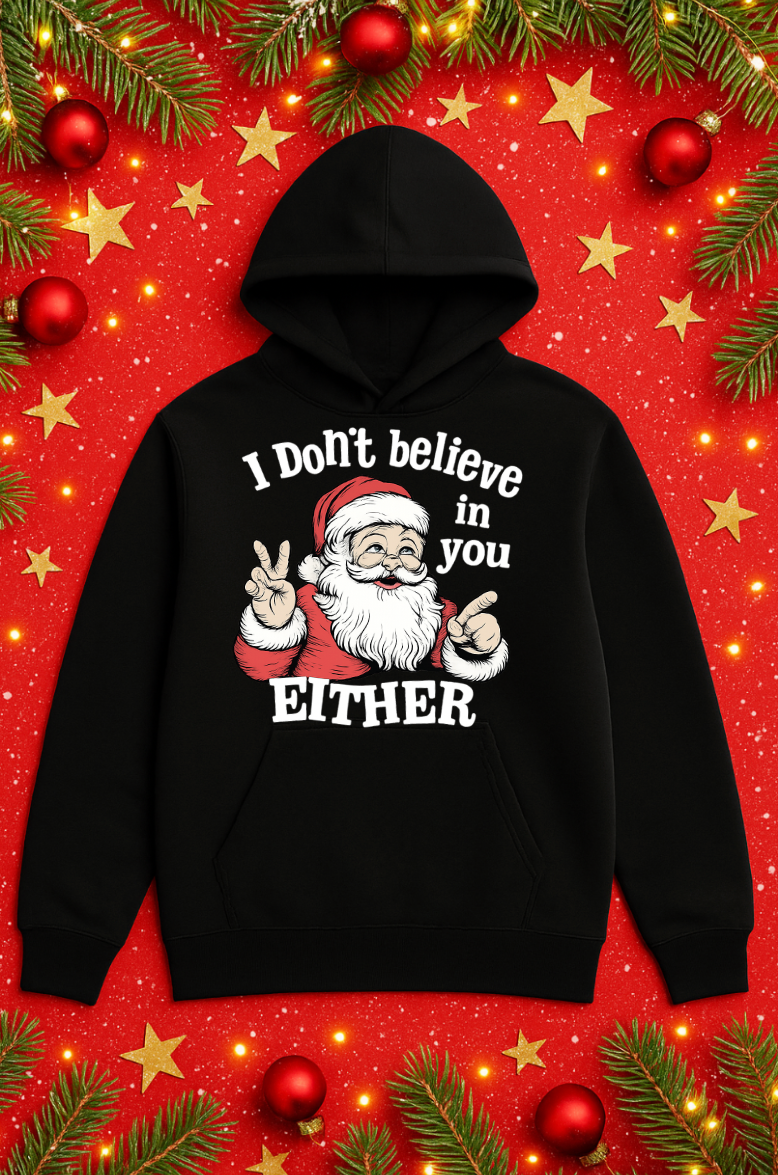 Black Christmas hoodie featuring a sarcastic Santa Claus graphic with the phrase “I Don’t Believe in You Either,” displayed on a festive red background with Christmas decorations.
