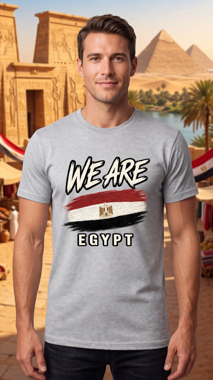 A man wearing a light gray t-shirt with a graphic that reads 'WE ARE EGYPT' above and below a stylized Egyptian flag, set against a background of the Egyptian pyramids and temples.