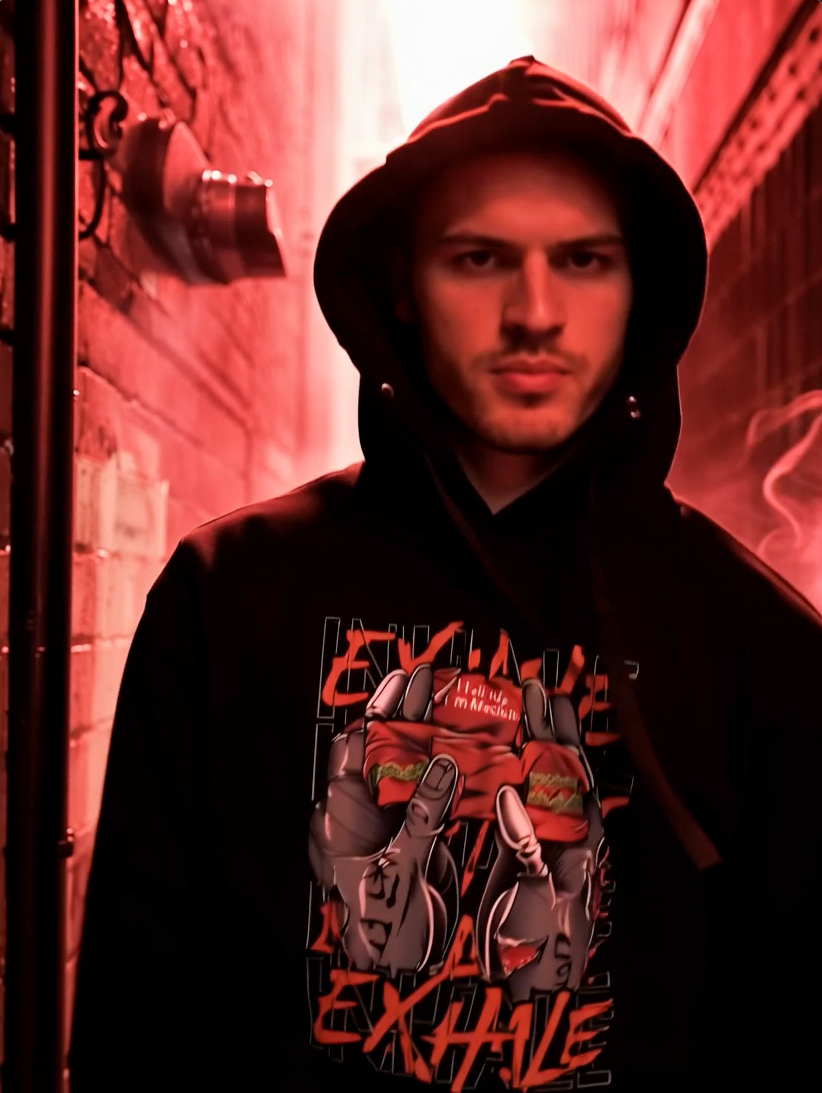 Man wearing red streetwear hoodie with colorful cartoon graphic in urban night setting