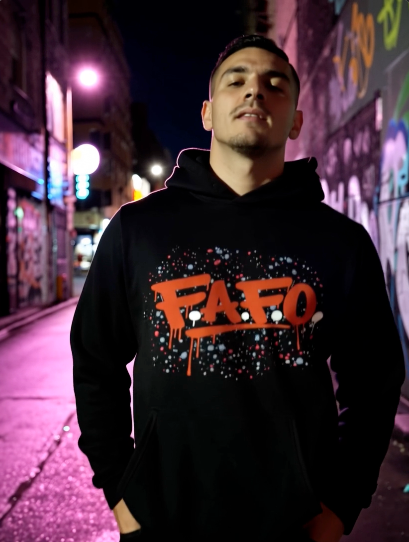 Man wearing black streetwear hoodie with FAFO graffiti graphic design in urban night setting