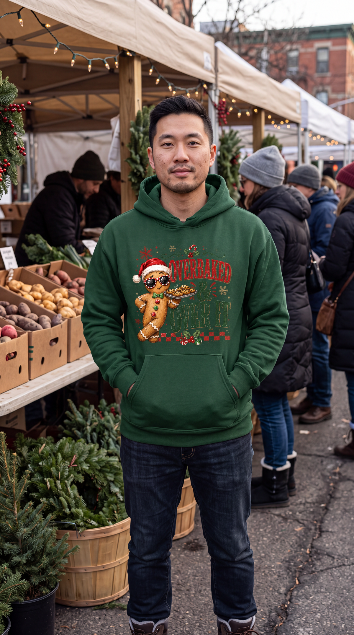 Man wearing forest green gingerbread Christmas hoodie with Overbaked and Over It design