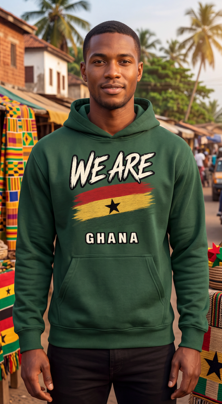 A man wearing a dark green hoodie with a 'WE ARE GHANA' graphic featuring the Ghana flag, standing in an outdoor market setting.