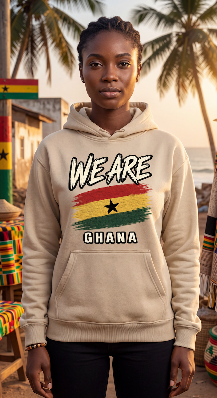 A woman wearing a beige hoodie with a 'WE ARE GHANA' graphic featuring the Ghana flag, standing outdoors in front of palm trees and a beach setting.
