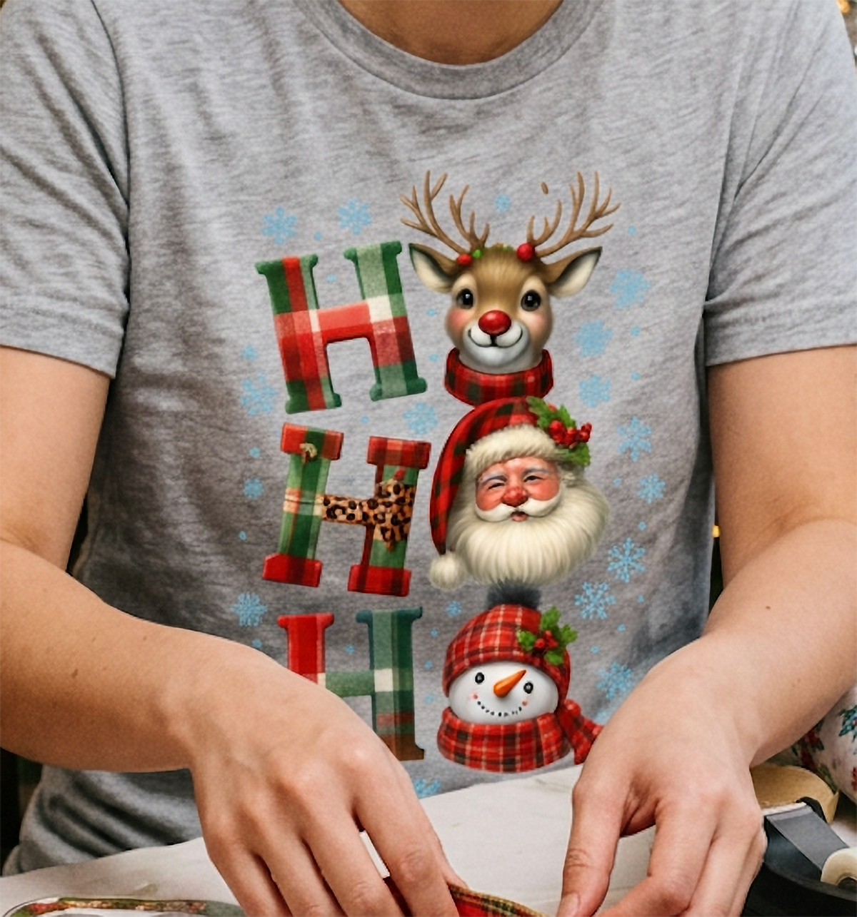 Close-up of heather gray Christmas t-shirt showing cute reindeer, Santa and snowman holiday graphic.