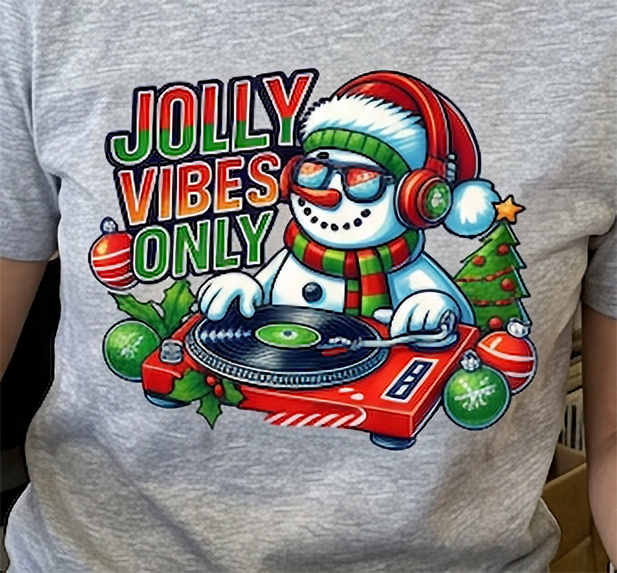 Heather Gray Close-Up: Close-up of the Jolly Vibes Only snowman DJ artwork on a heather gray Christmas t-shirt.