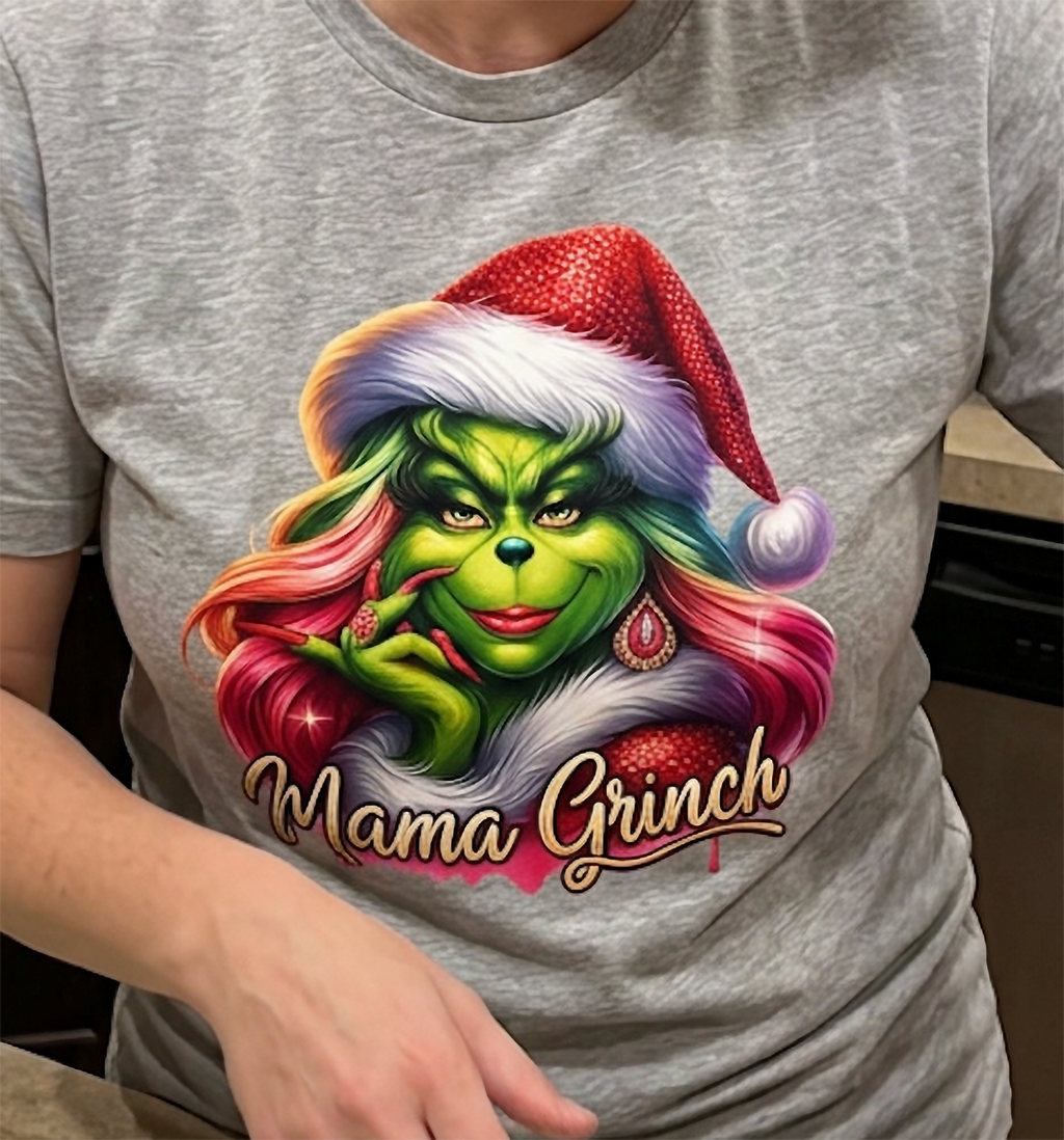 Close-up of heather gray Mama Grinch Christmas shirt showing colorful holiday graphic and festive pink hairstyle.