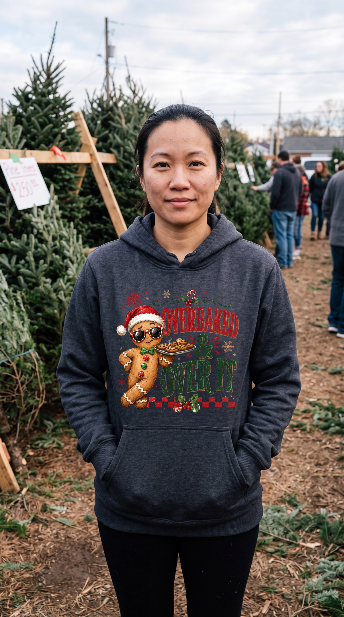 Woman wearing gray Overbaked and Over It gingerbread Christmas hoodie