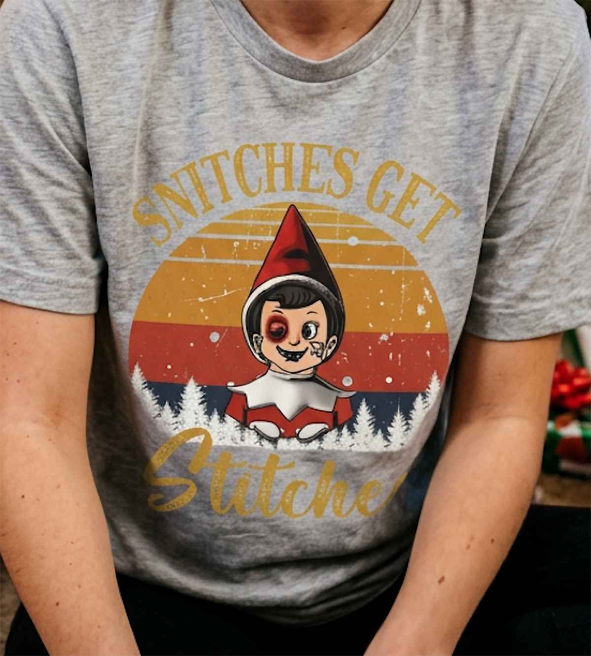 Close-up of funny Christmas elf graphic on a heather gray t-shirt with distressed retro holiday artwork.