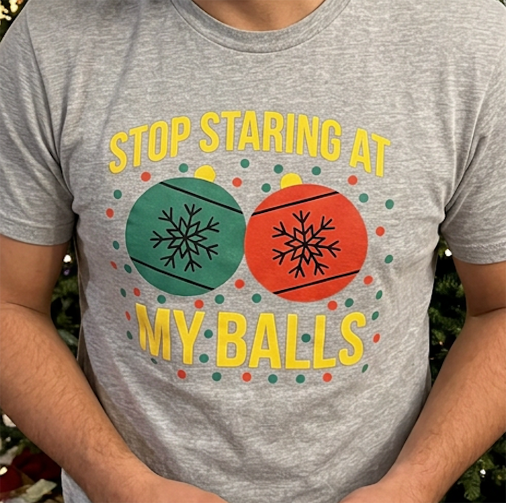 Close-up of heather gray Christmas shirt featuring red and green ornaments and bold yellow lettering.