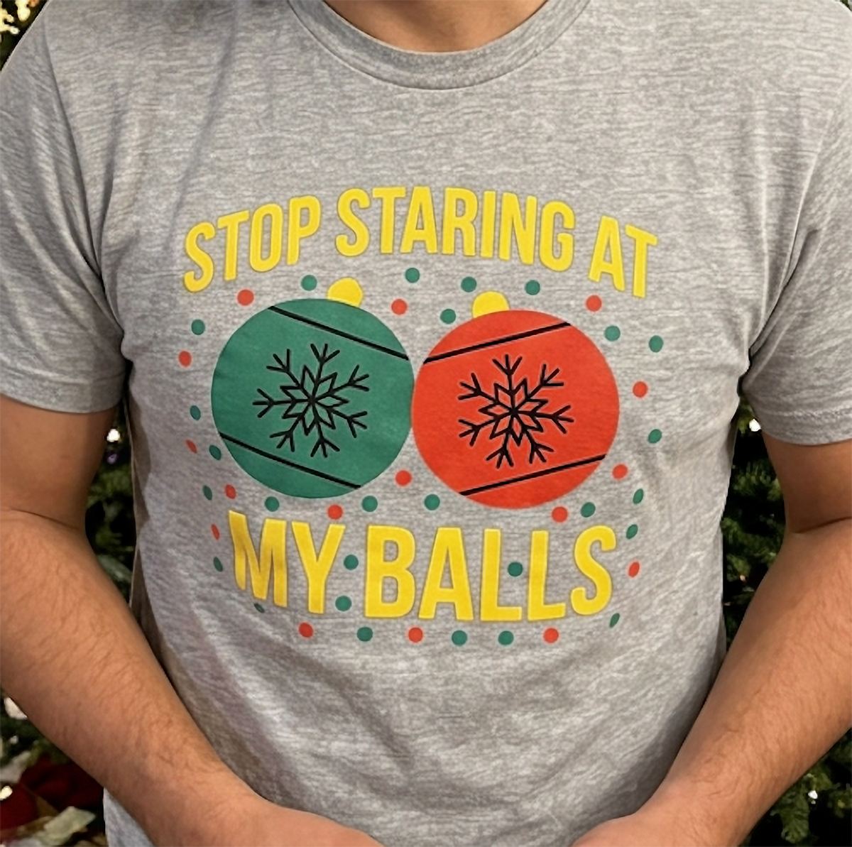 Close-up of heather gray Christmas shirt featuring red and green ornaments and bold yellow lettering.