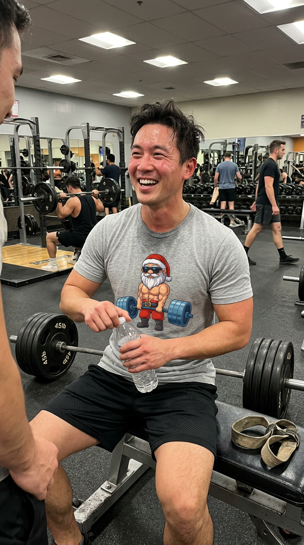 Man wearing a heather gray Swole Santa Christmas workout t-shirt at the gym featuring a muscular Santa weightlifting graphic.