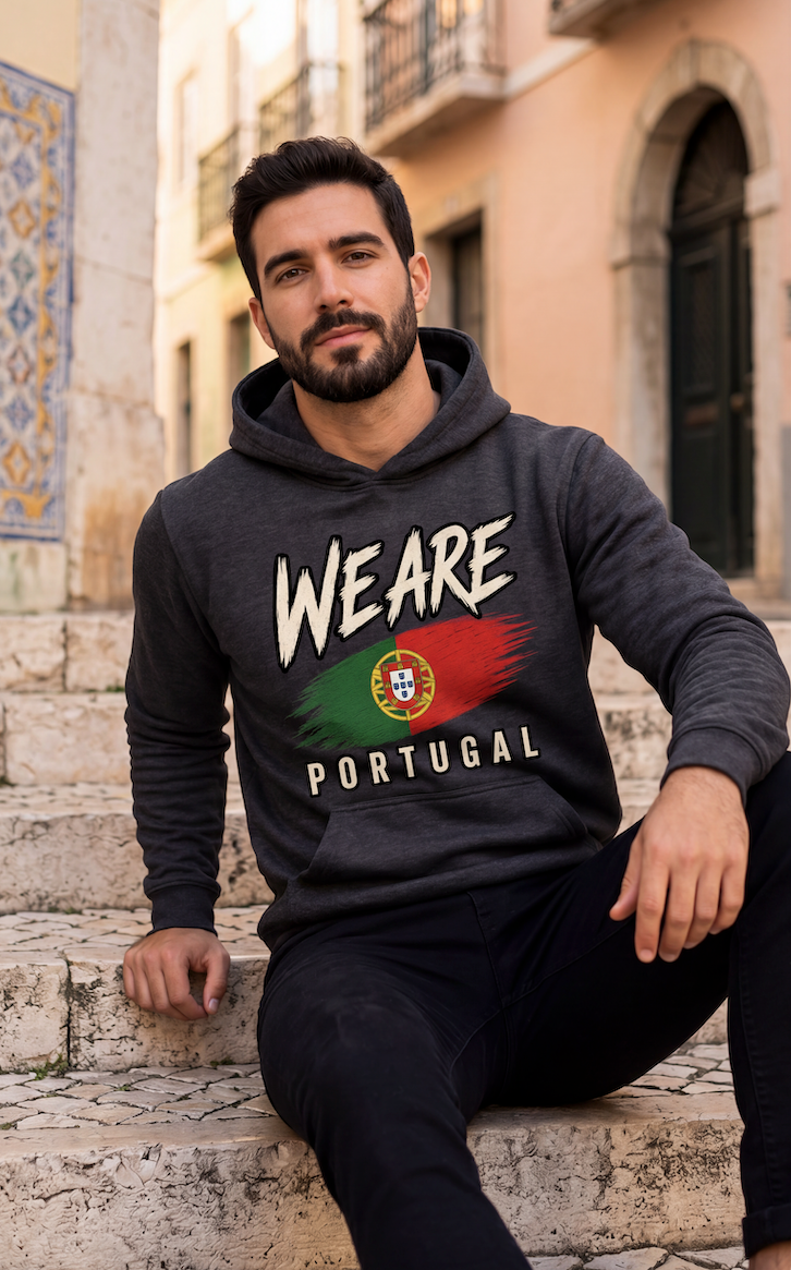 A man wearing a dark gray hoodie with 'WE ARE PORTUGAL' and the Portuguese flag graphic printed on the front, sitting on stone steps in an outdoor urban setting.