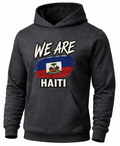 A dark gray heather pullover hoodie with a graphic on the chest that reads 'WE ARE HAITI' above and below a stylized Haitian flag, shown on a plain white background.