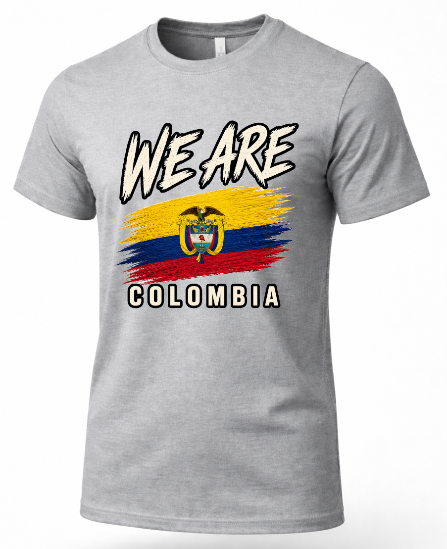 A heather gray short-sleeve t-shirt featuring a graphic print of the text 'WE ARE' above a stylized Colombian flag and 'COLOMBIA' below, shown on a plain white background.