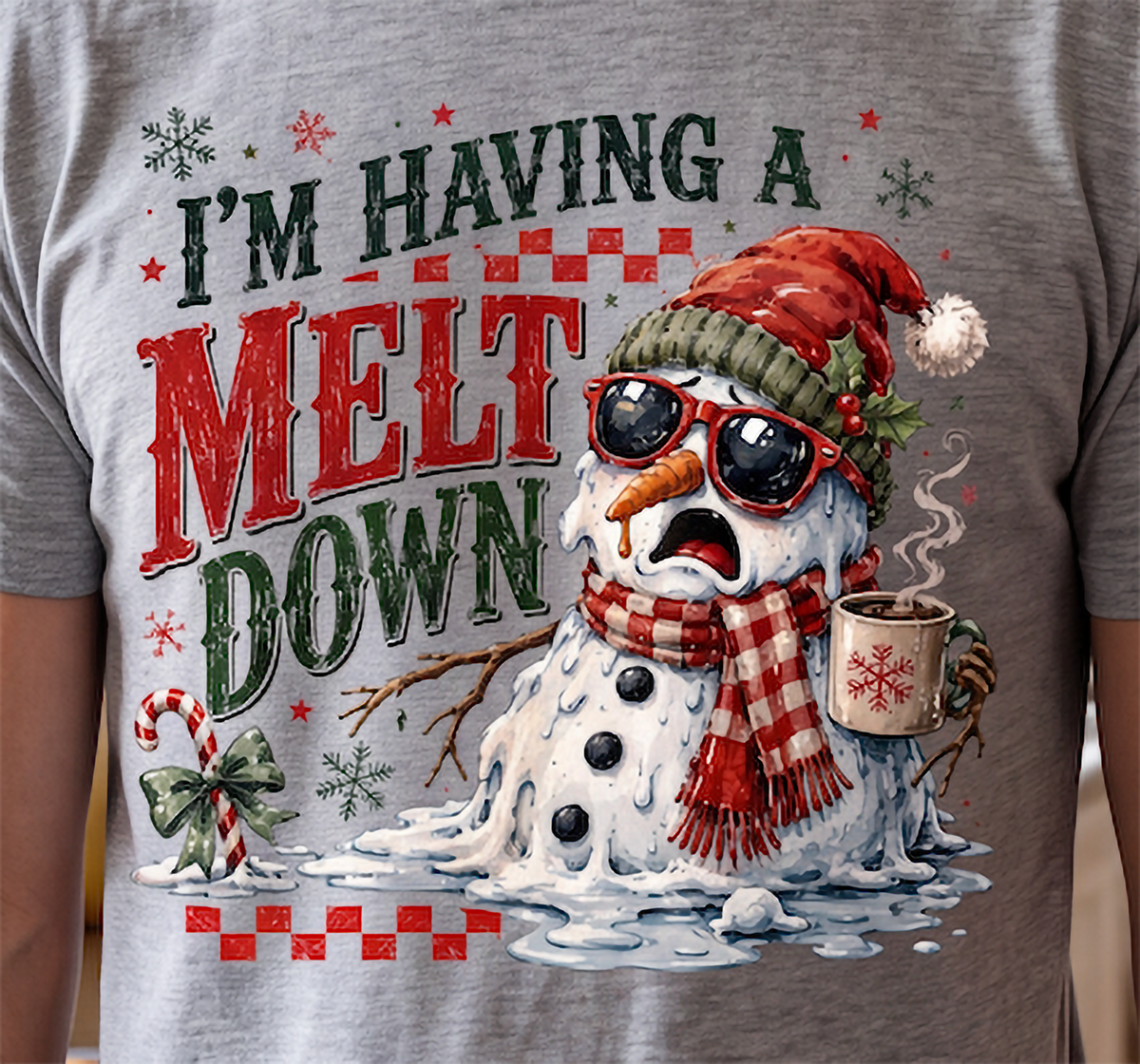 Close-up of heather gray I’m Having a Meltdown Christmas shirt with melting snowman, Santa hat and holiday drink.