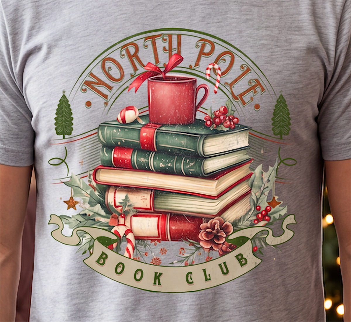 Close-up of North Pole Book Club Christmas graphic printed on gray shirt featuring cozy vintage holiday book design.