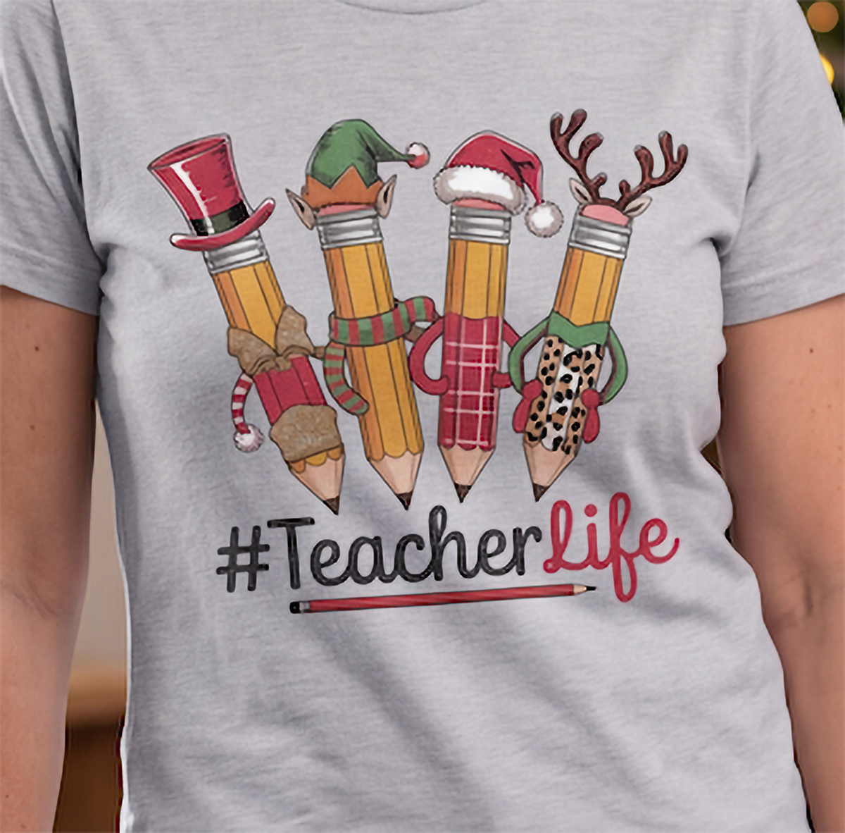 Close-up of heather gray Teacher Life Christmas shirt showing colorful festive pencil artwork.
