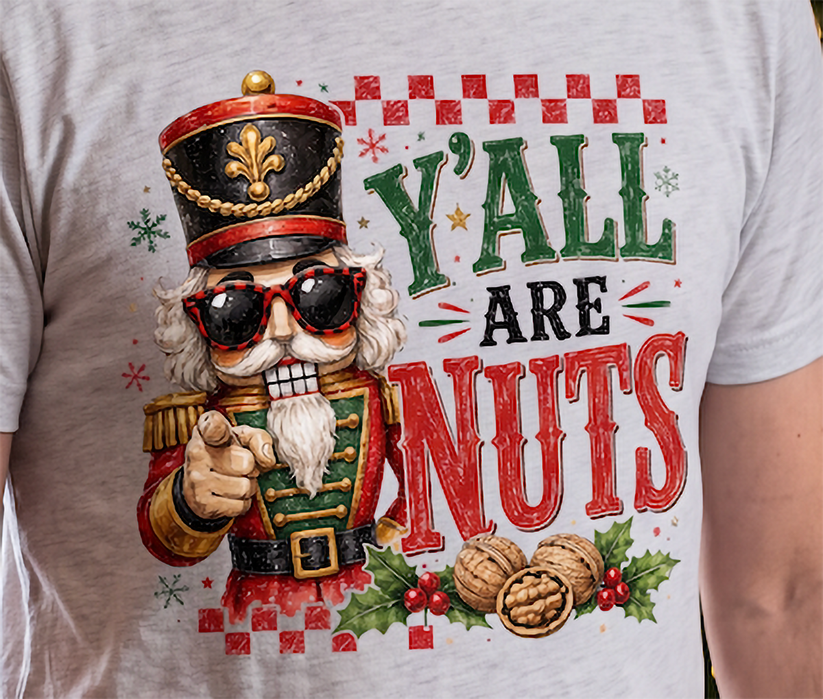 Close-up of heather gray Y’all Are Nuts Christmas shirt featuring nutcracker, walnuts and holly
