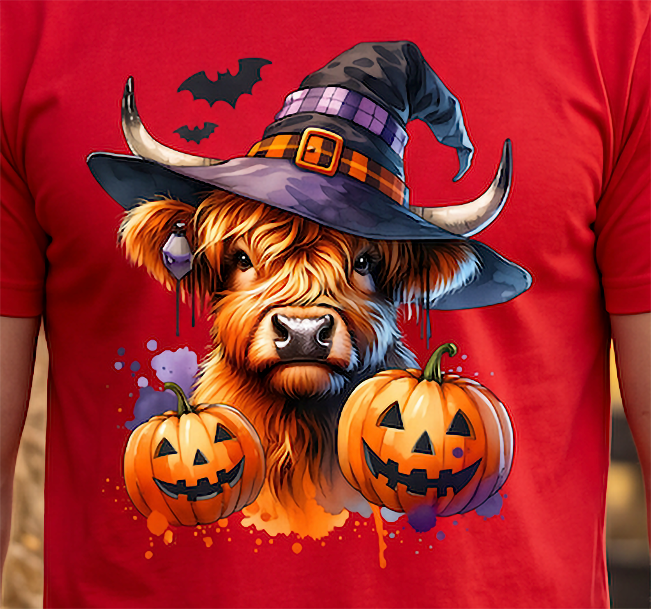 Close-up of witchy Highland cow Halloween graphic on red shirt with jack-o'-lantern pumpkins