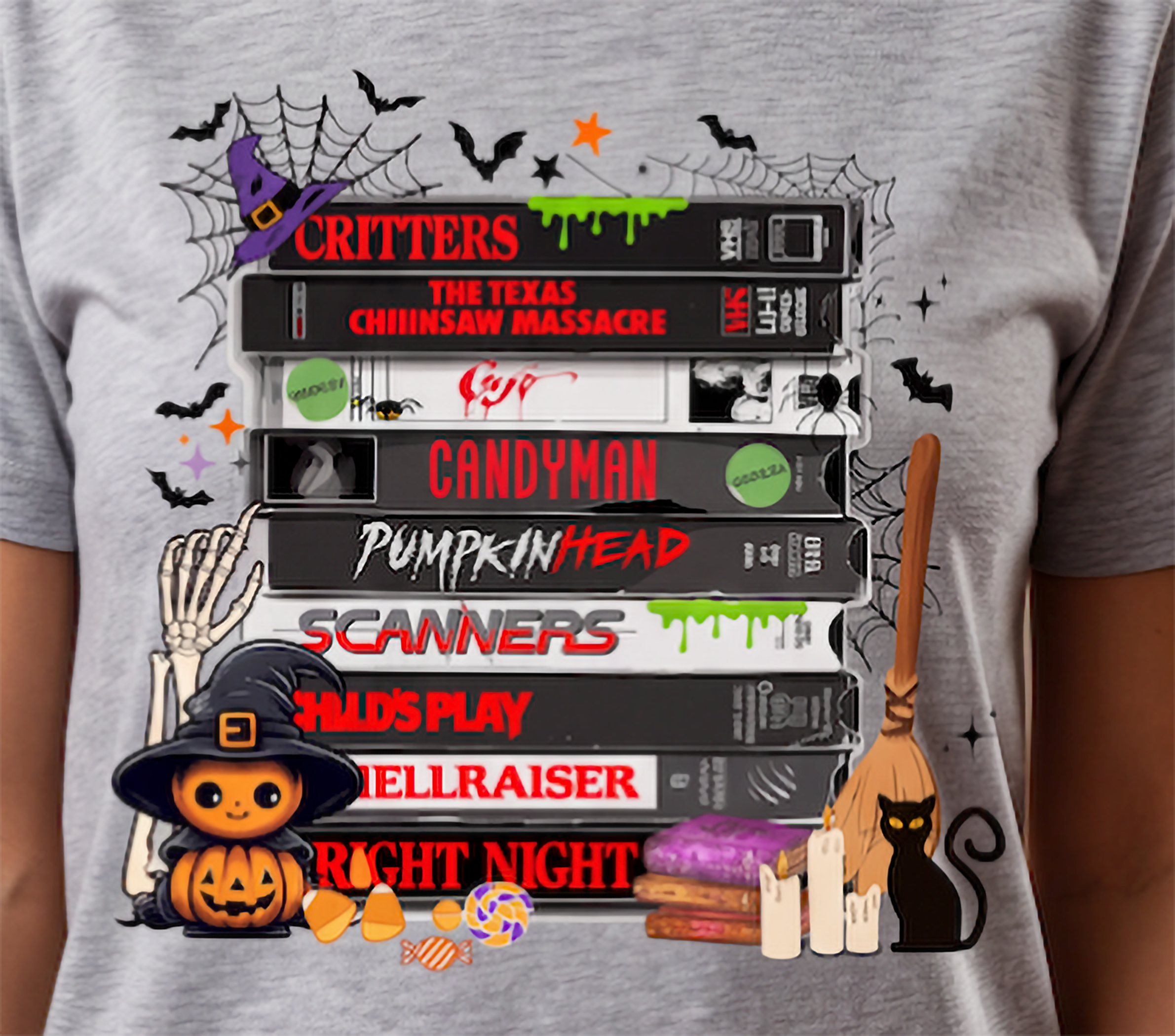 Close-up of retro horror VHS tape graphic on heather gray shirt with Halloween bats, spiderwebs, pumpkin, candy, candles and black cat.
