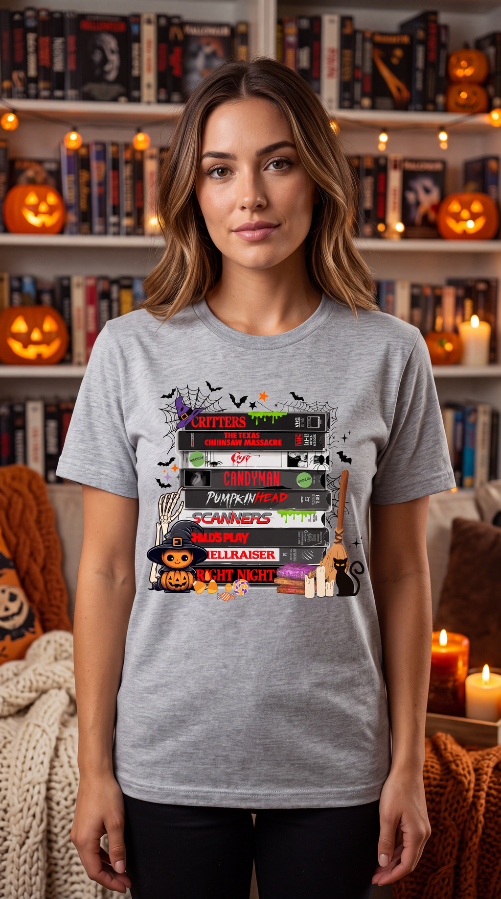 Woman wearing a heather gray horror movie VHS T-shirt featuring stacked retro scary movie tapes and Halloween artwork.