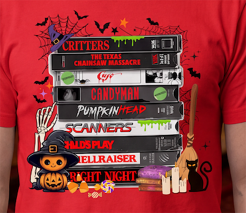 Close-up of horror movie VHS graphic on red T-shirt featuring stacked retro scary movie tapes, bats, spiderwebs and Halloween details.
