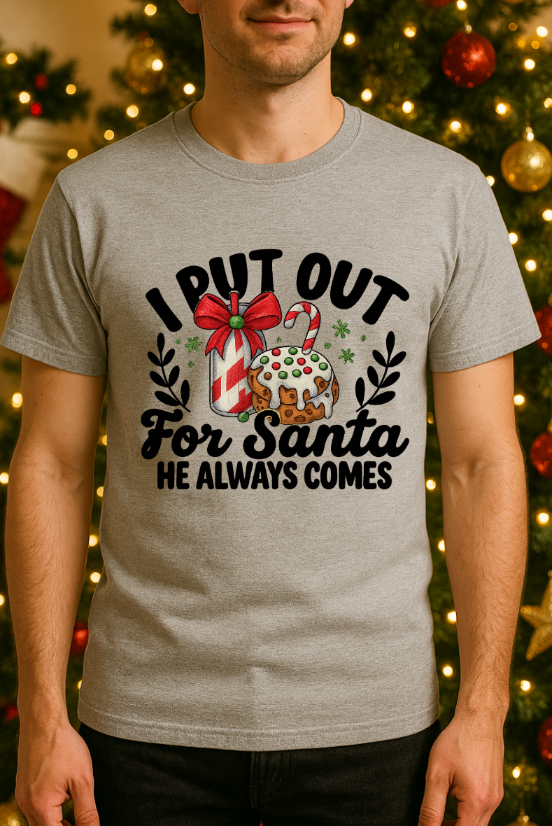 Man wearing a gray Bella + Canvas 3001 unisex t-shirt with “I Put Out for Santa” funny Christmas graphic, adult humor holiday shirt shown in front of a decorated Christmas tree