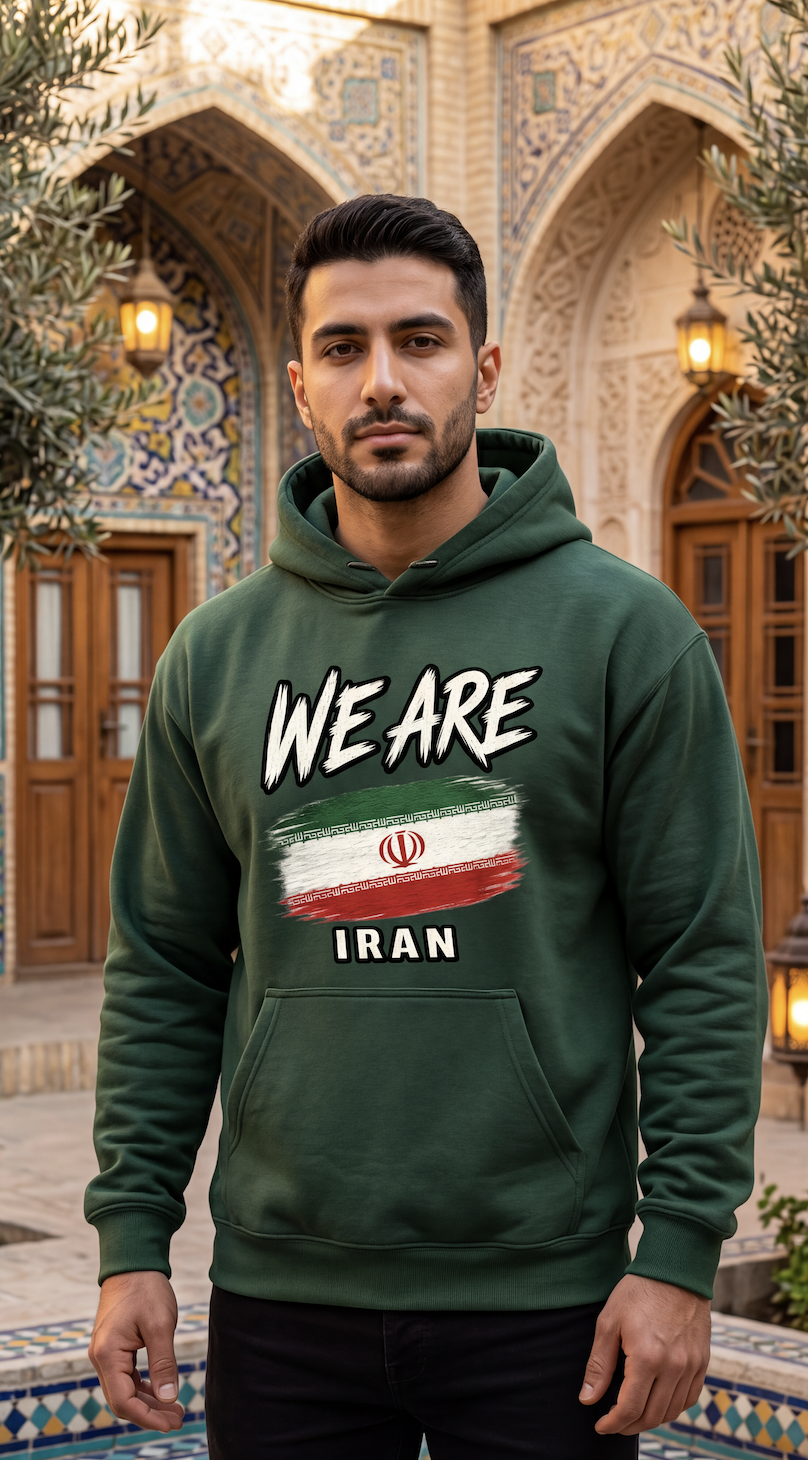 A man wearing a Forest Green hoodie with a graphic print that reads 'WE ARE' above an Iranian flag design and 'IRAN' below, standing in front of an ornate architectural background with arches and columns.