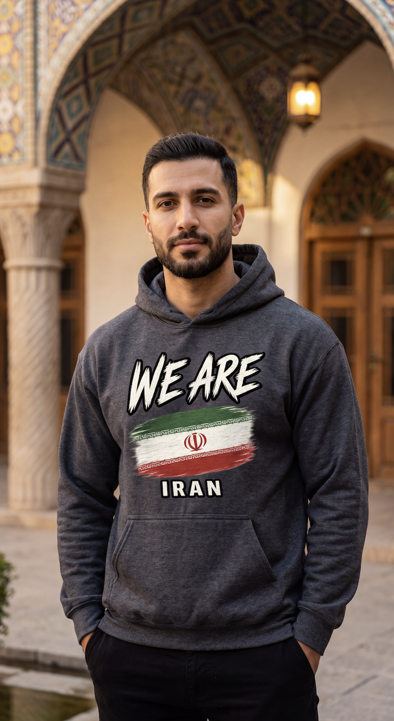 A man wearing a dark gray hoodie with a graphic print that reads 'WE ARE' above an Iranian flag design and 'IRAN' below, standing in front of an ornate architectural background with arches and columns.