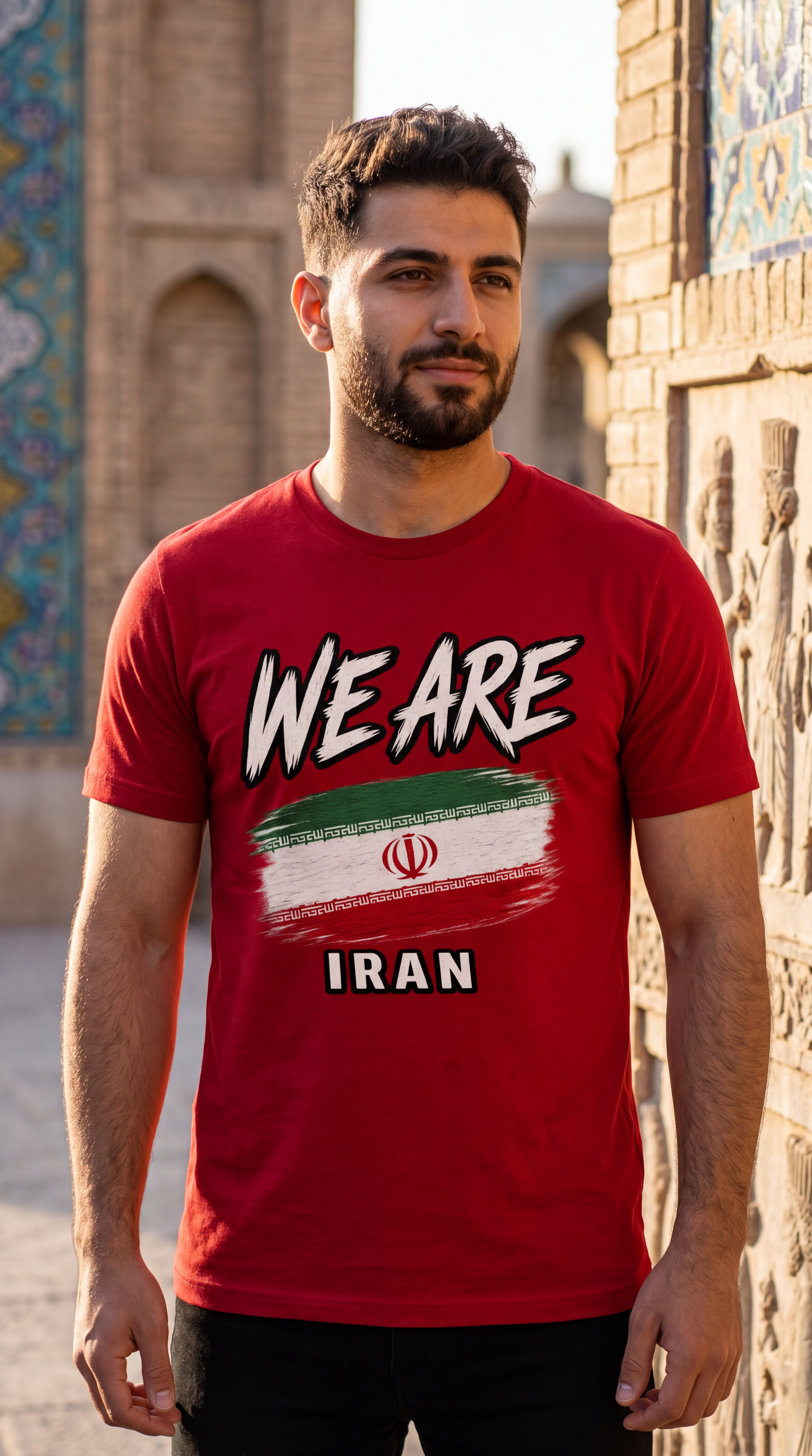 A man wearing a red graphic t-shirt with 'WE ARE IRAN' and the Iranian flag printed on the front, standing outdoors against a historic tiled wall.