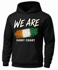 A black pullover hoodie with a graphic print on the front. The design features the text 'WE ARE' in a distressed white font above a horizontal tricolor flag in orange, white, and green, with 'IVORY COAST' printed below in white.
