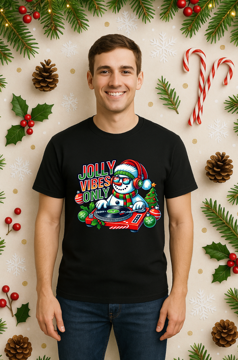 Man wearing a black Bella+Canvas 3001 Christmas t-shirt with a DJ snowman graphic and “Jolly Vibes Only” text, styled with festive holiday decorations