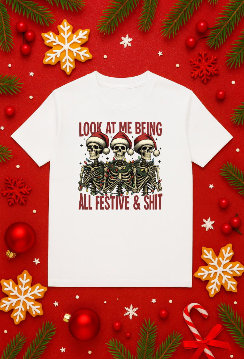 White Christmas skeleton shirt with three skeletons wearing Santa hats and holiday lights, featuring the text “Look At Me Being All Festive & Shit” on a festive red background