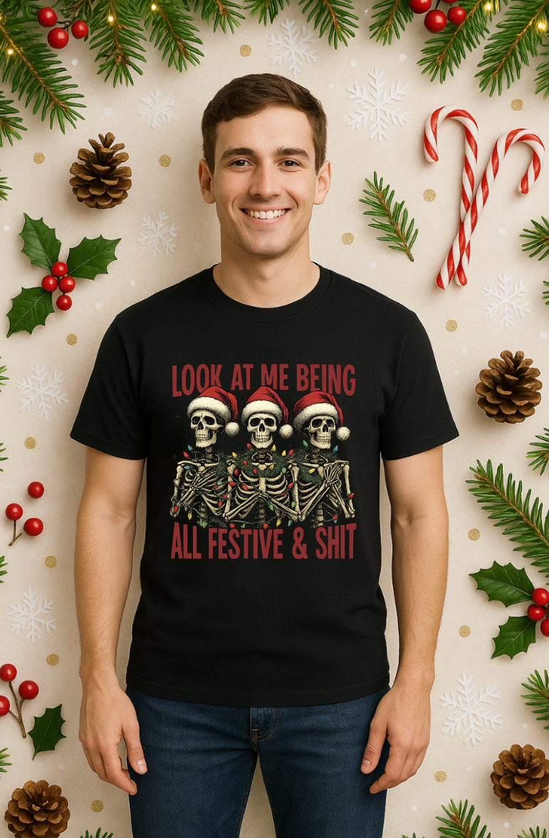 Man wearing a black Christmas skeleton shirt featuring three skeletons in Santa hats with the text “Look At Me Being All Festive & Shit,” standing against a festive holiday background
