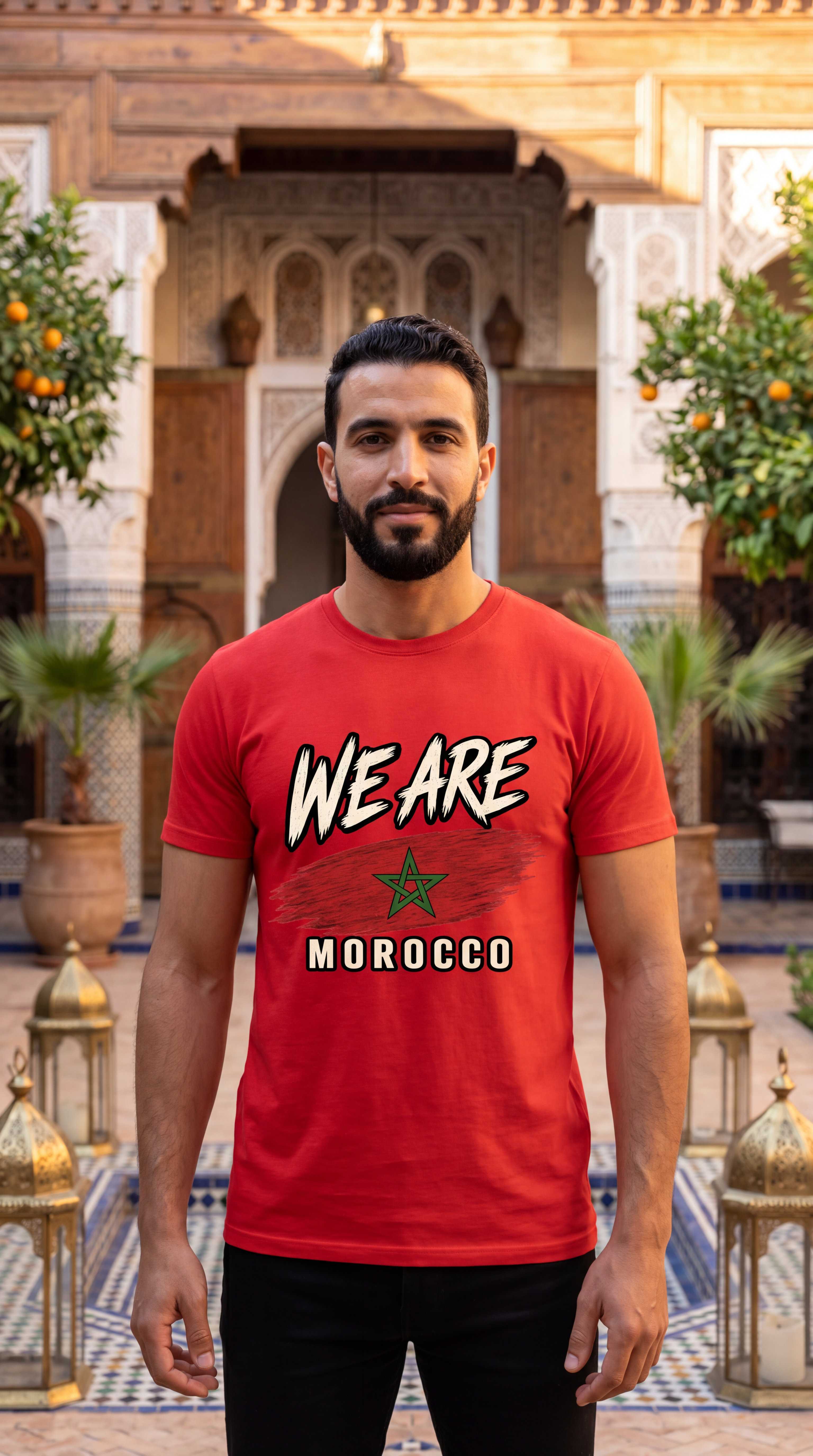 A man wearing a red graphic t-shirt with 'WE ARE MOROCCO' and a green star printed on the front, standing in a Moroccan courtyard with ornate arches, lanterns, and potted plants.