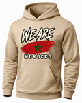 A beige pullover hoodie with a graphic on the chest featuring the text 'WE ARE MOROCCO' over a red brushstroke design with a green star, representing the Morocco flag.