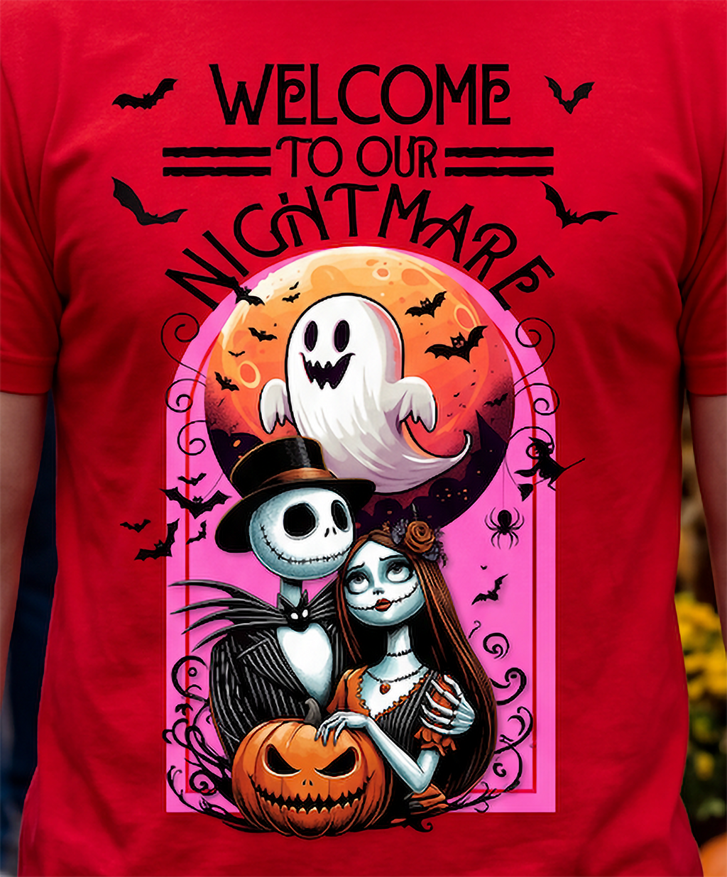 A red short-sleeve graphic t-shirt featuring a Halloween-themed illustration with the text 'WELCOME TO OUR NIGHTMARE'. The design includes Jack Skellington and Sally in front of a jack-o'-lantern, with a ghost against an orange moon in the background, surrounded by black bats and spiders.
