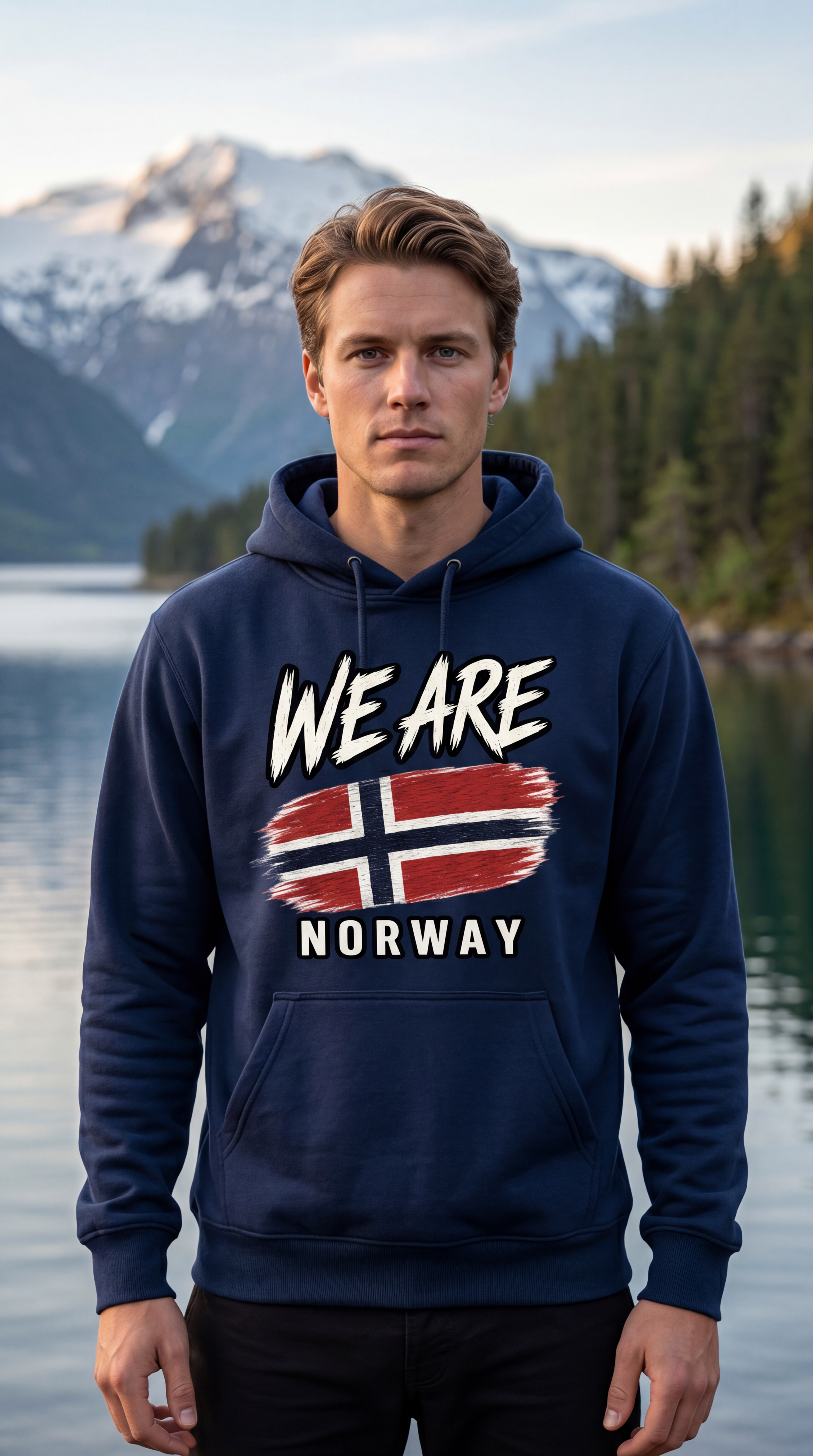 A man wearing a navy blue hoodie with a 'WE ARE NORWAY' graphic featuring the Norwegian flag, standing in front of a scenic mountain and lake background.