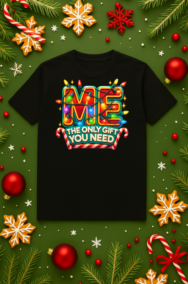 Black Christmas t-shirt with colorful holiday lights spelling “ME” and the phrase “The Only Gift You Need,” displayed on a festive green background with ornaments, candy canes, snowflakes, and pine branches.