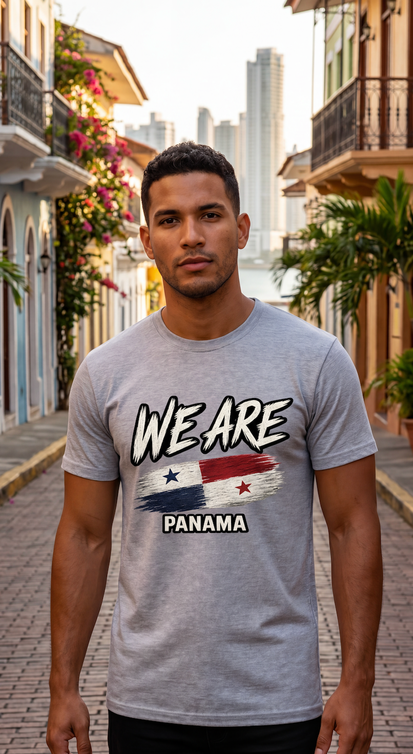 A man wearing a heather gray t-shirt with a graphic that reads 'WE ARE PANAMA' and features the Panamanian flag, standing on a cobblestone street in front of colonial-style buildings.