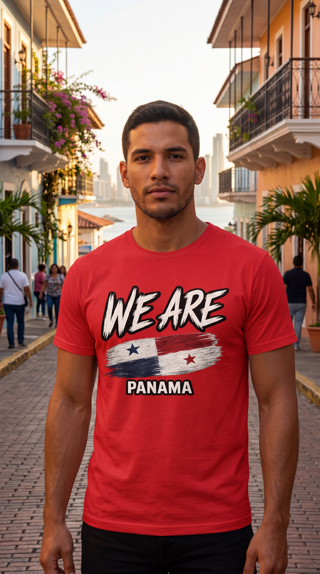 A man standing on a cobblestone street wearing a red t-shirt with a graphic that reads 'WE ARE PANAMA' above a painted flag design.