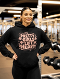 Woman wearing gym hoodie with “Pretty Girls Lift Heavy” text in fitness gym setting