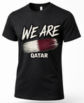 A black short-sleeve crewneck t-shirt featuring a distressed graphic print of the word 'WE ARE' in white above a stylized Qatar flag, with 'QATAR' printed below in white.