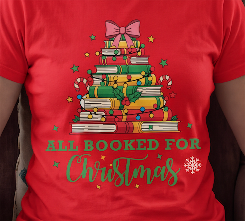 Close-up of red All Booked for Christmas shirt featuring the festive stacked books and holiday decorations.